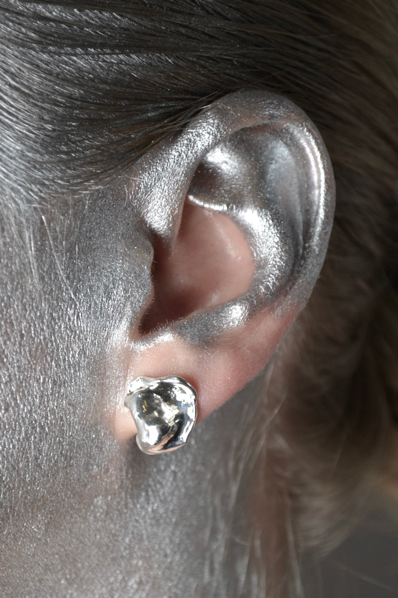 One molten looking stud earring with backing in sterling silver on ear